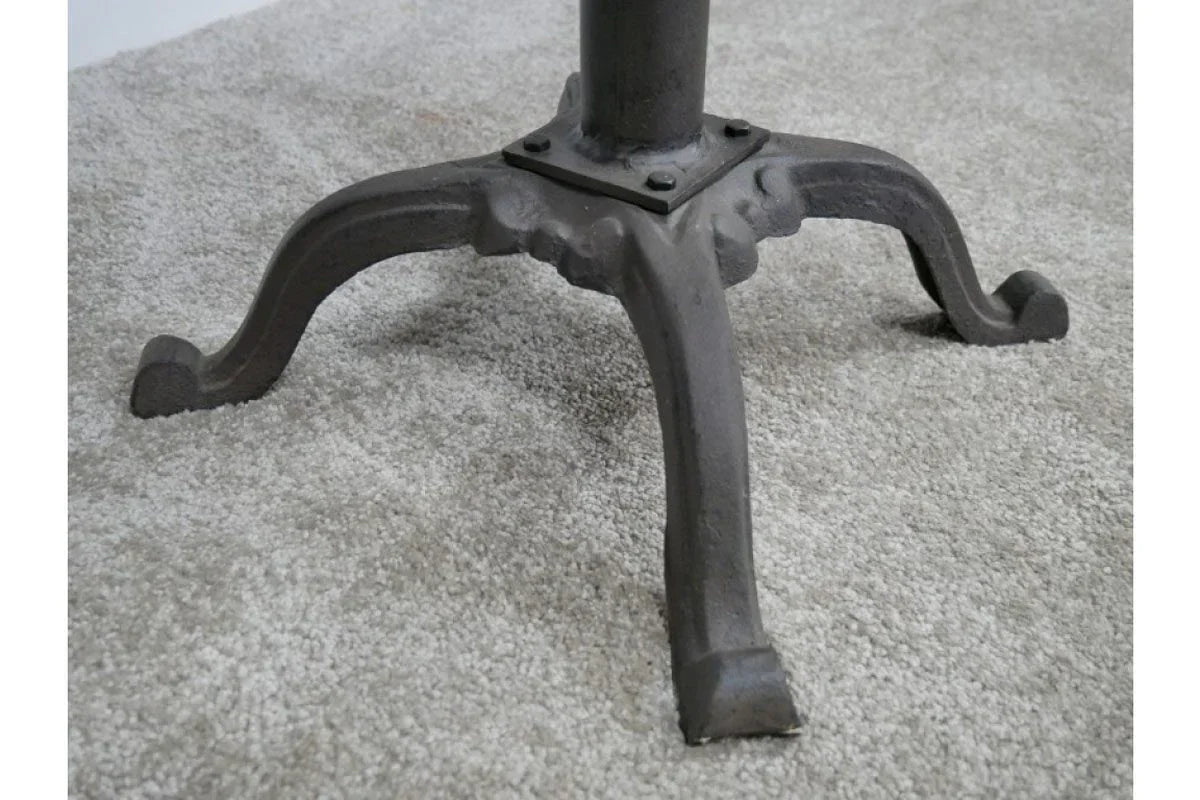 Black cast iron table base with curved legs on light carpet