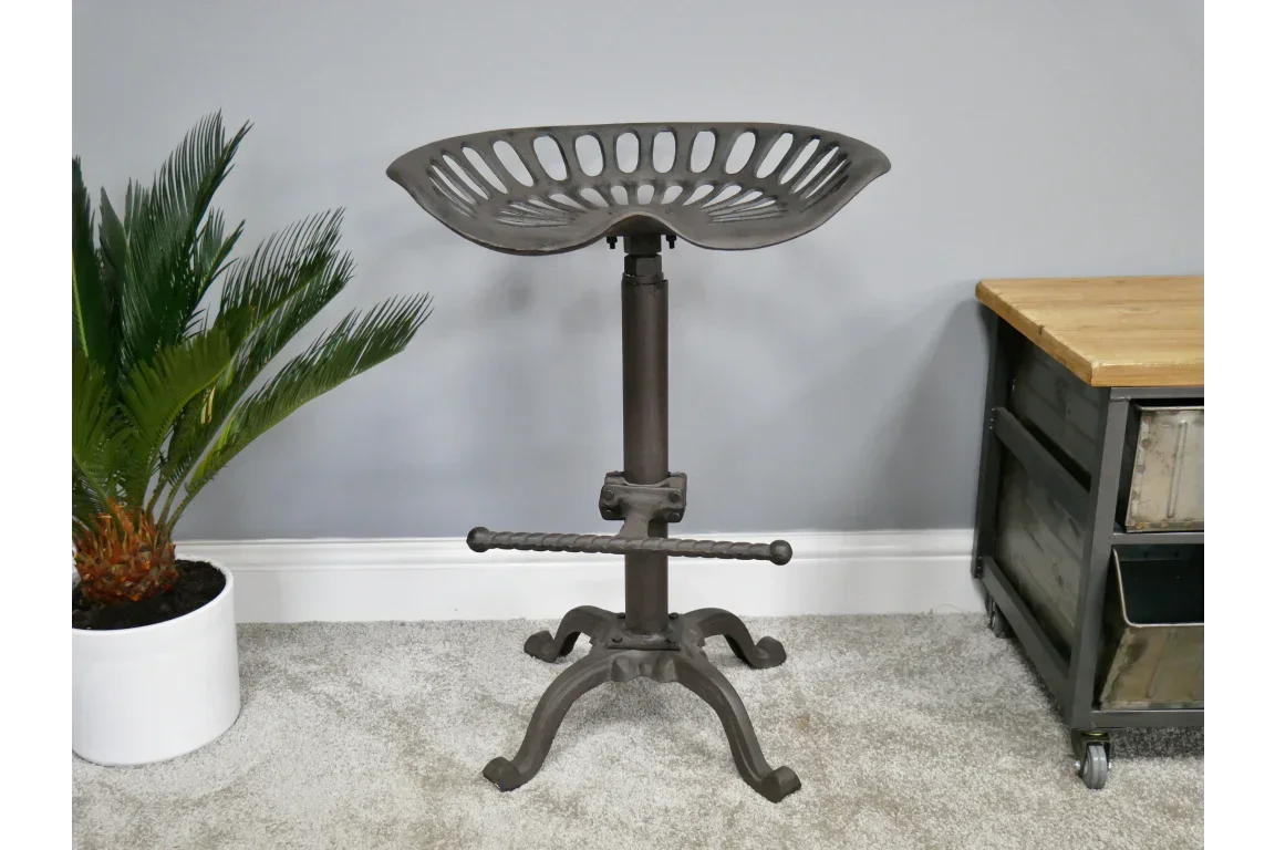 Industrial metal bar stool with tractor seat and footrest on carpeted floor