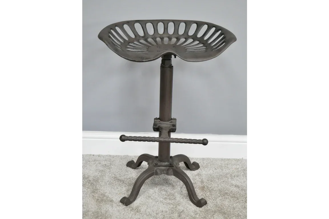 Industrial metal bar stool with tractor seat and footrest on carpet