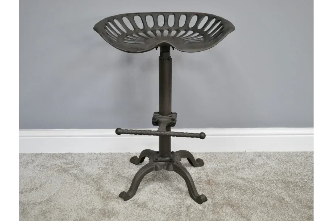 Industrial metal bar stool with tractor seat and footrest on carpet