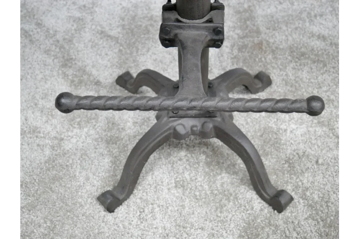 Cast iron table base with ornate twisted stretcher on grey carpet