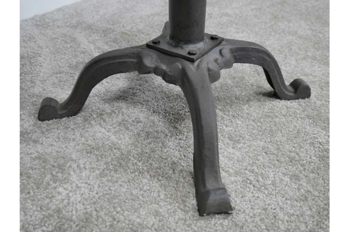 Black cast iron table base with four curved legs on light grey carpet