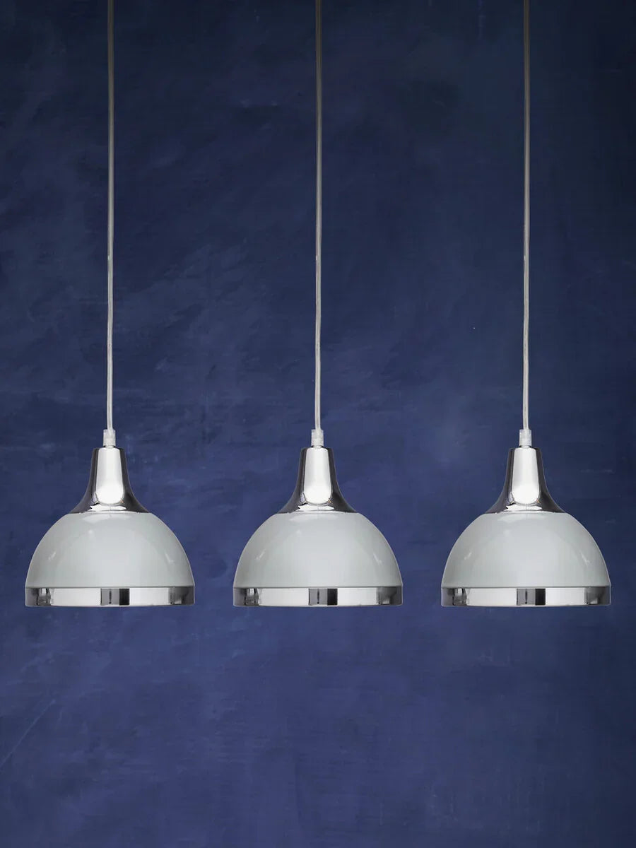 Set of three chrome pendant lights with white shades against a dark blue background