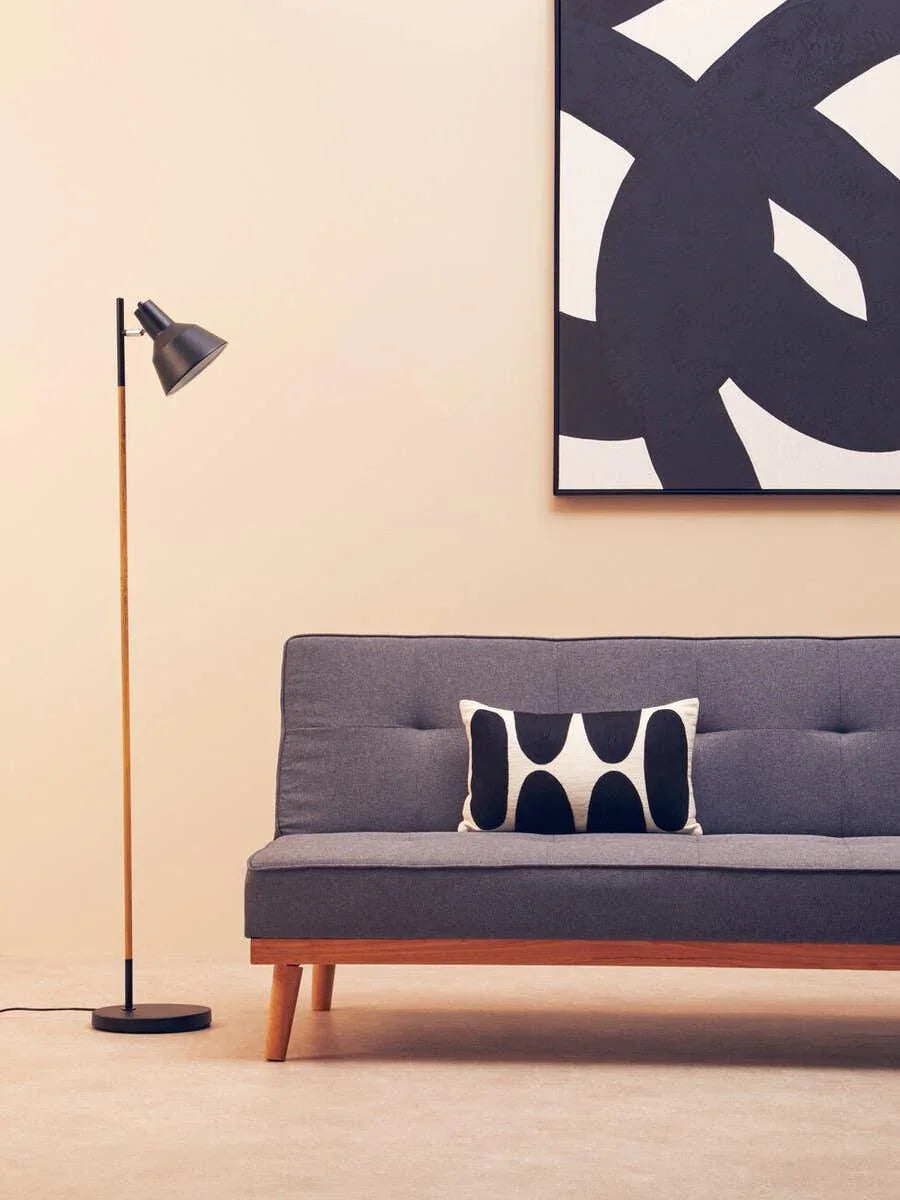 Grey fabric sofa with wooden legs, black and white cushion, floor lamp, abstract wall art