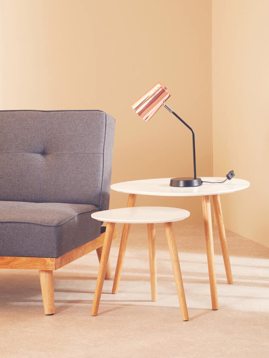 Set of two white side tables with wooden legs beside grey sofa and copper table lamp
