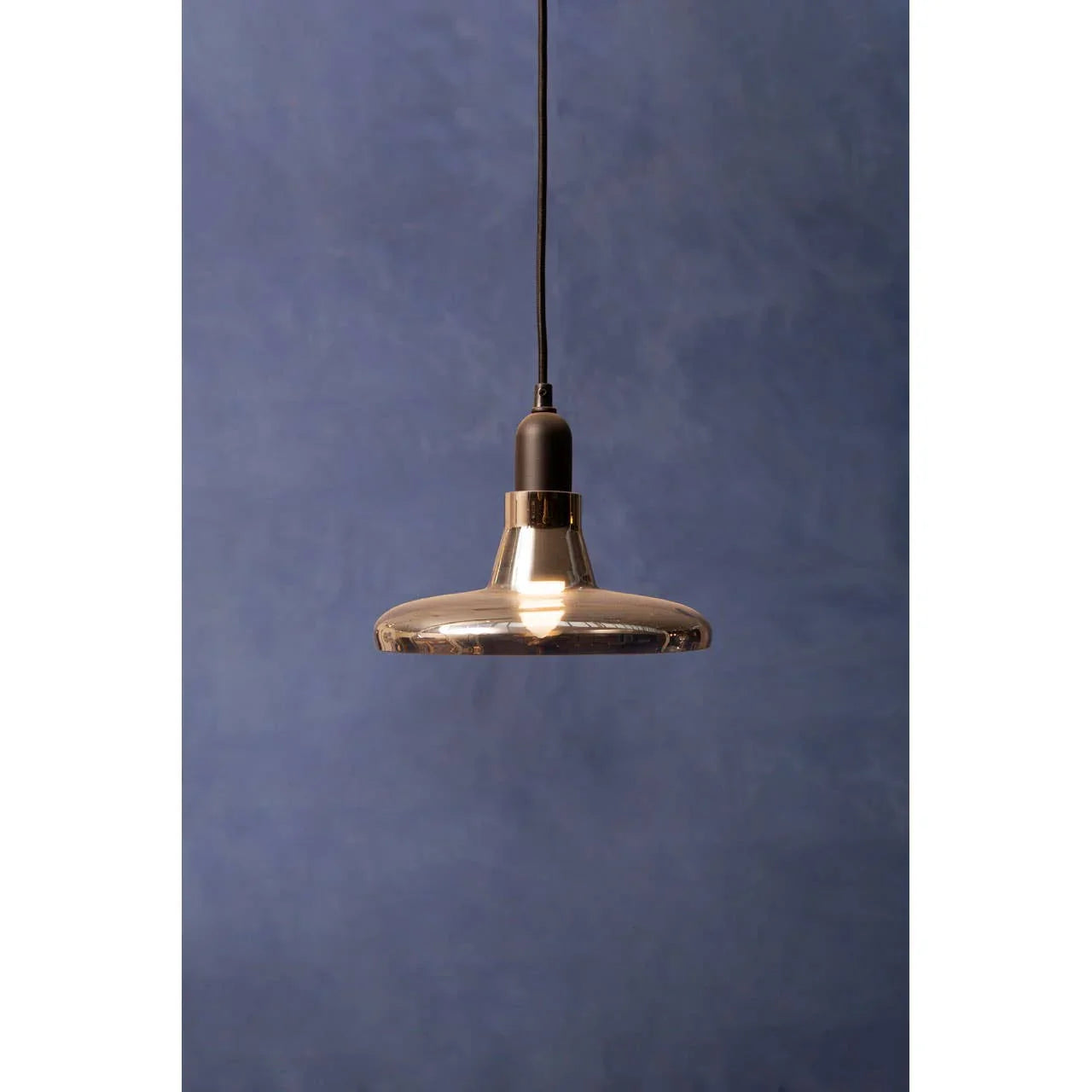 smoked glass pendant light with black cord against blue wall
