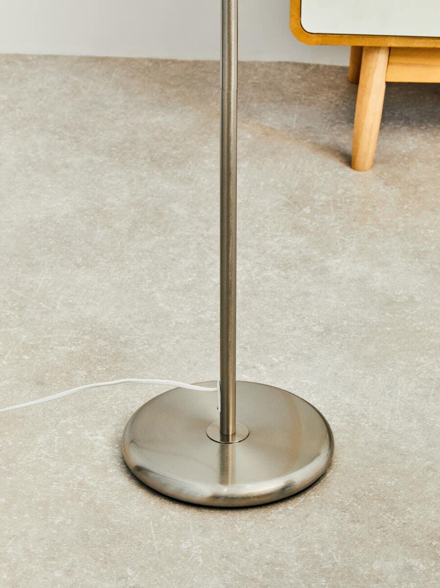 Brushed steel floor lamp base with power cable on stone effect flooring