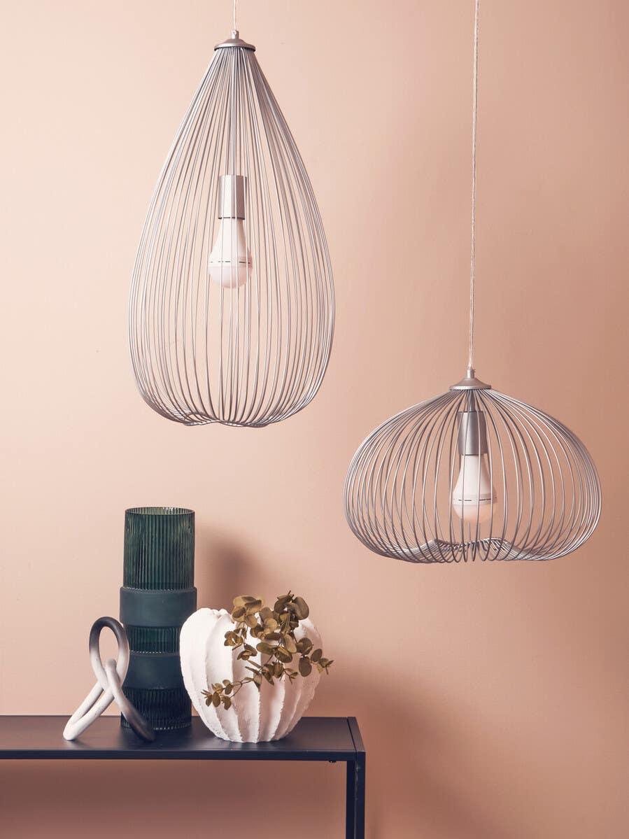 Modern wire pendant ceiling lights above black console table with green vase and white planter