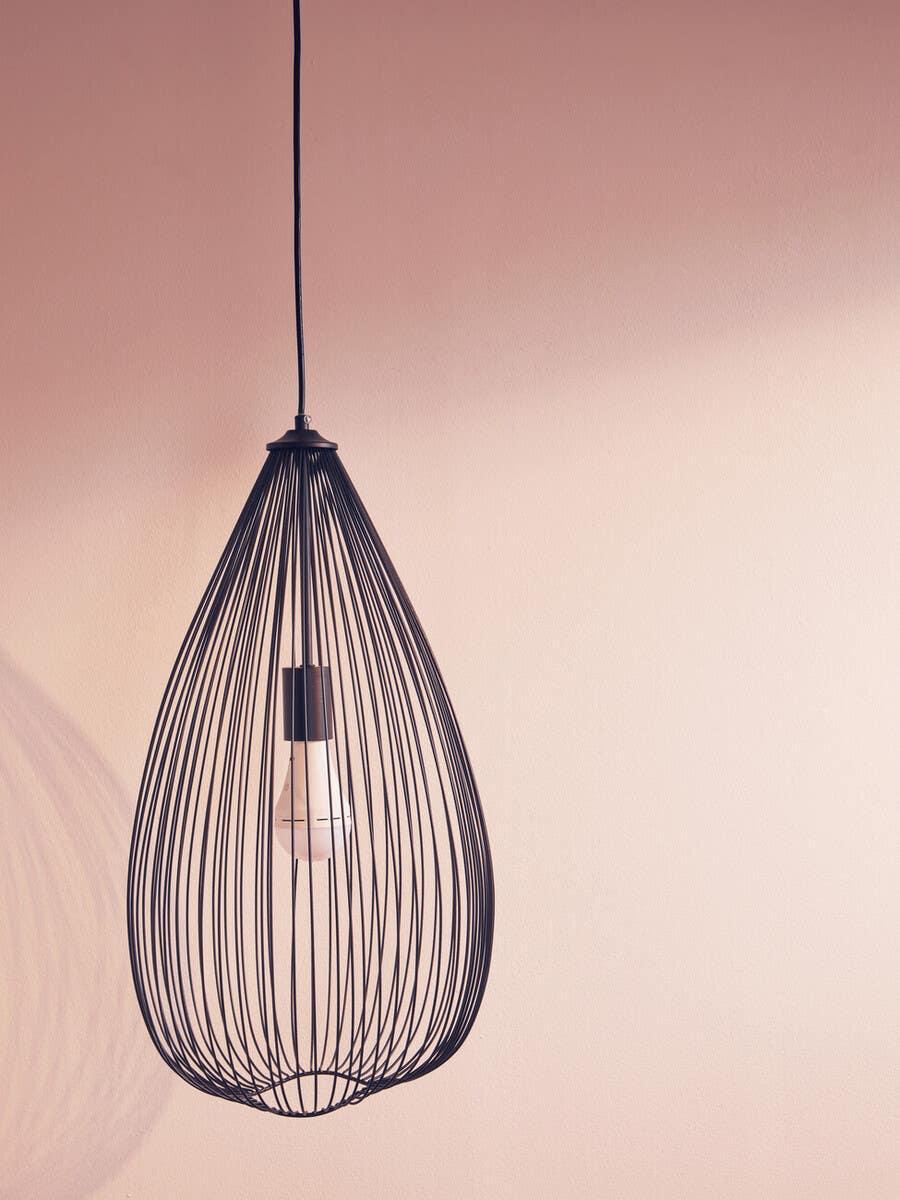Black wire pendant light with exposed bulb against a neutral wall