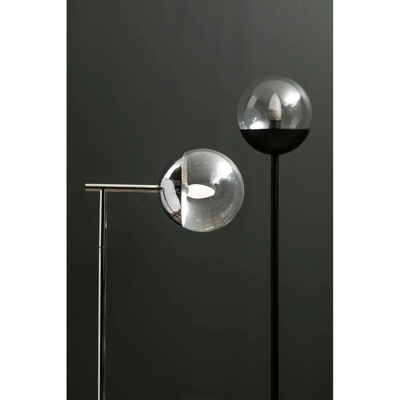 Modern glass globe floor lamps with chrome and black metal stands against a dark wall