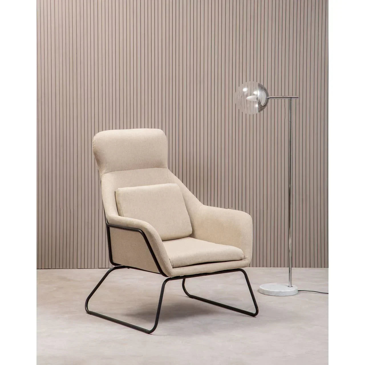 Beige accent armchair with metal legs and cushions beside a modern floor lamp