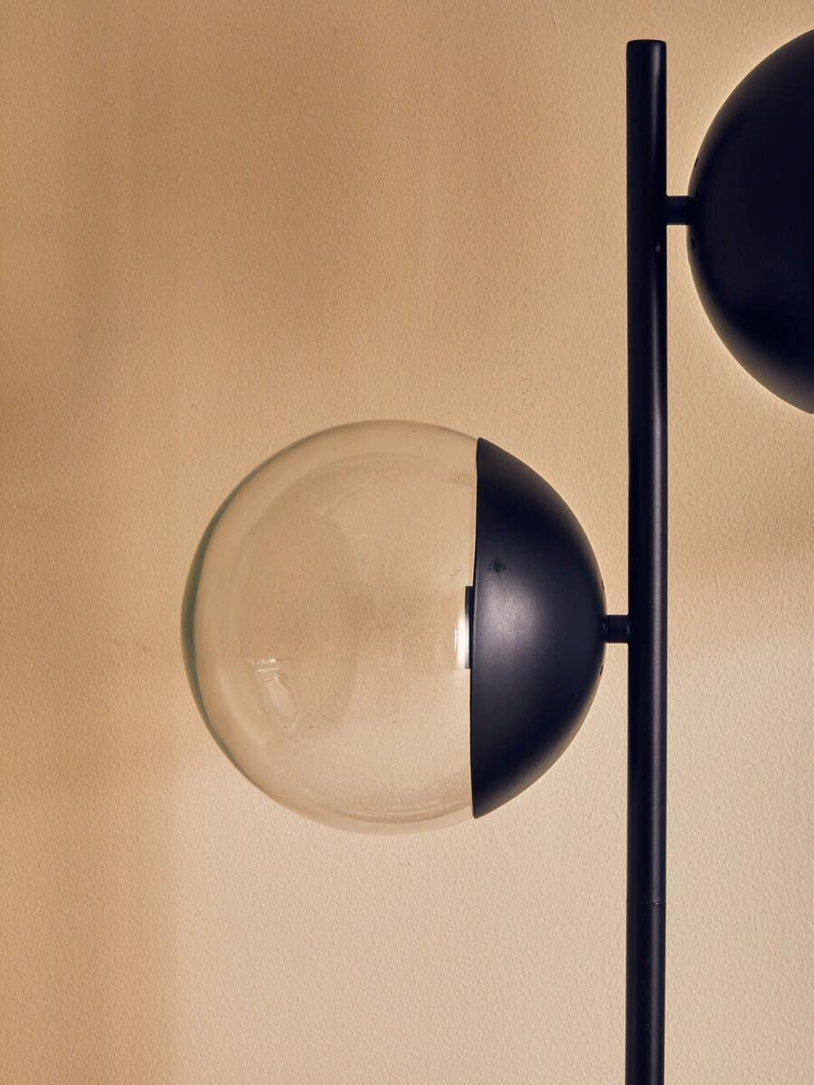 Modern black and glass floor lamp globe detail against beige wall