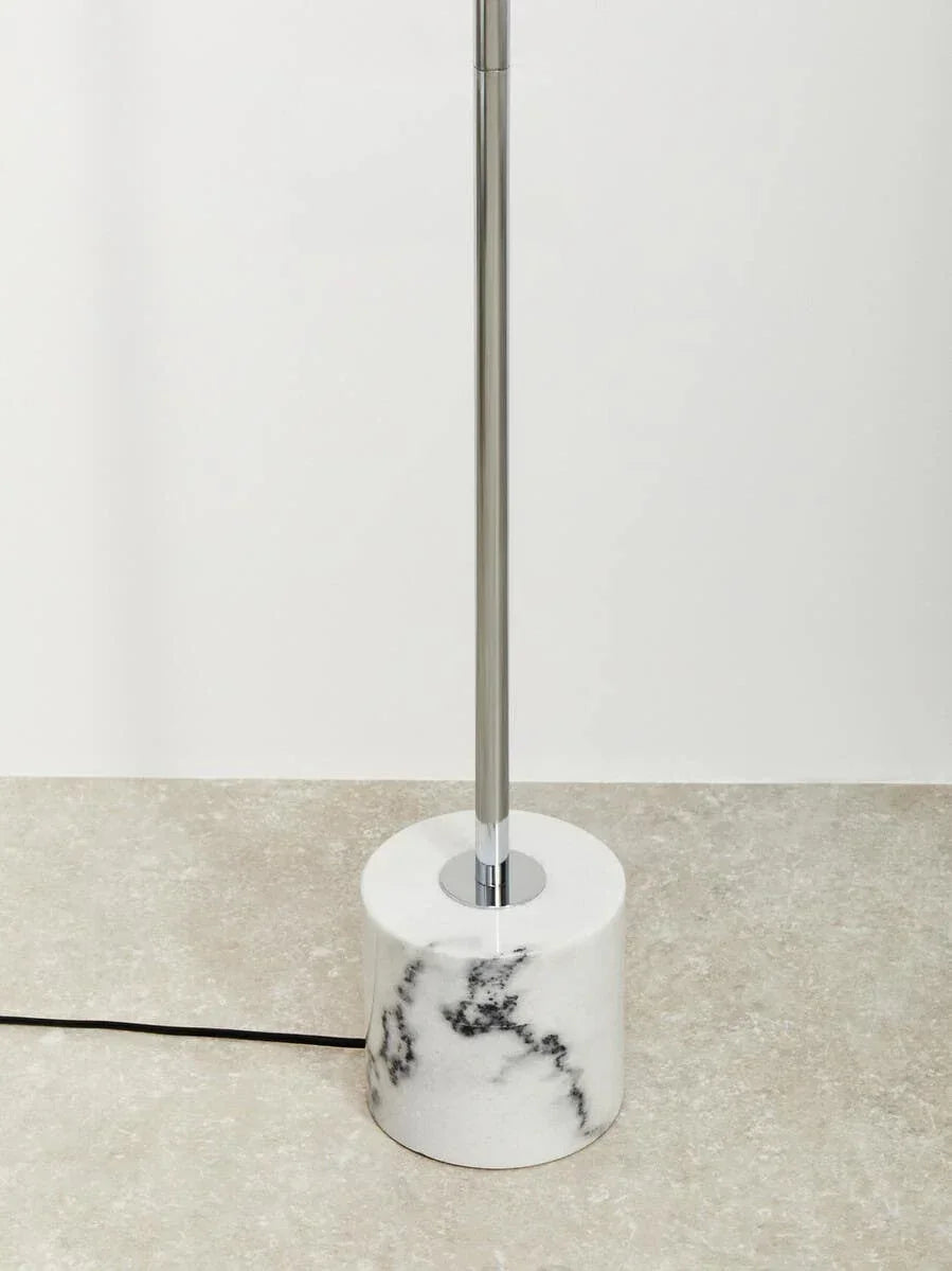 Modern floor lamp with chrome stand and white marble base on tiled floor