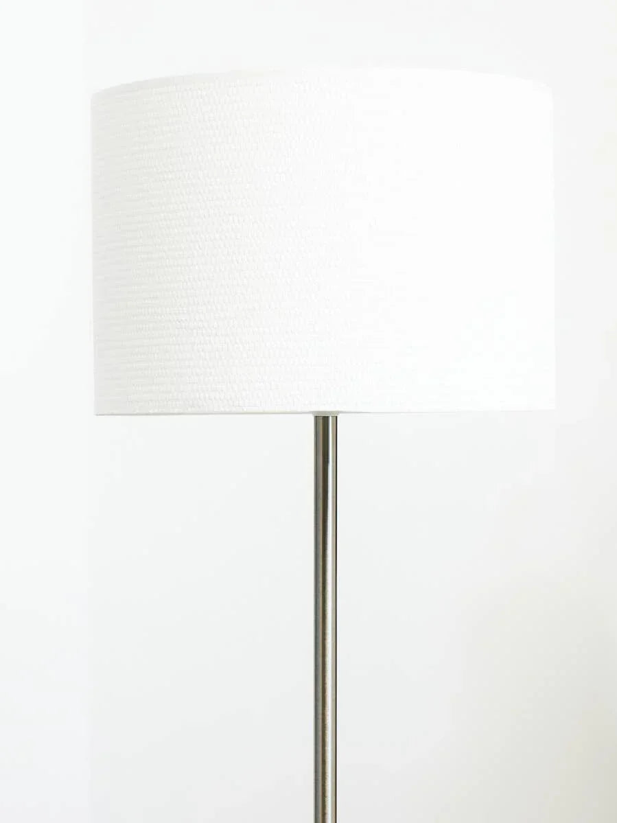 Modern floor lamp with white fabric shade and slim metal stand against white background