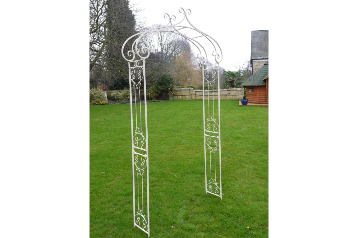 White metal garden arch with decorative scrollwork on lawn
