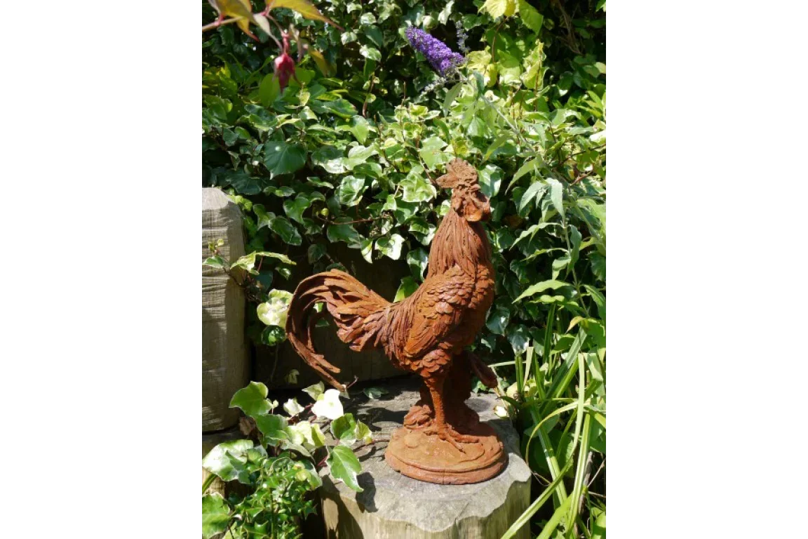 rustic cast iron rooster garden ornament on wooden stump among lush green foliage