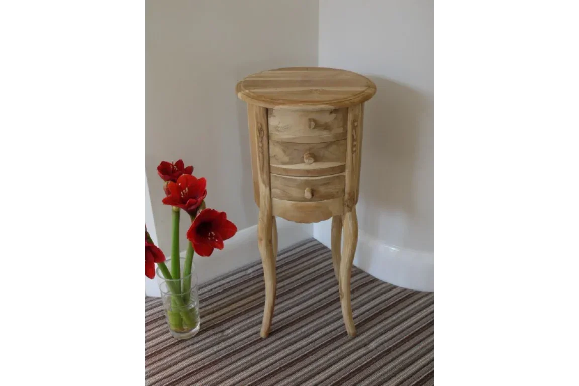 Round wooden bedside table with three drawers and curved legs on striped carpet