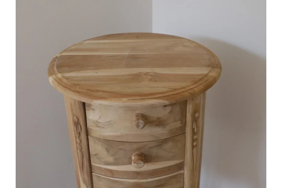 Round wooden bedside table with three drawers and natural finish against a white wall
