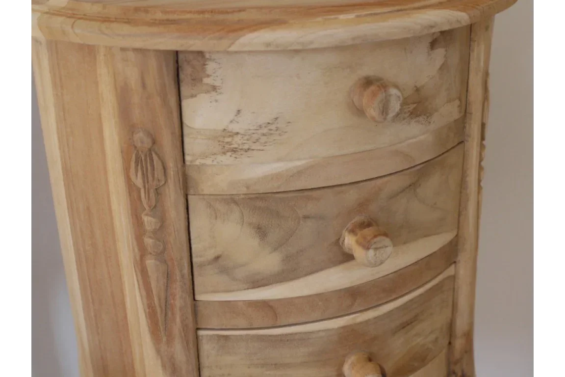 Natural wood chest of drawers with carved detail and round handles, close-up view