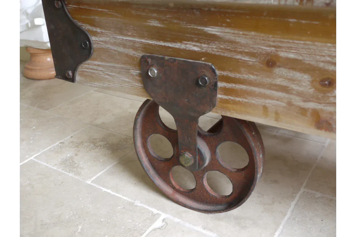 Close-up of industrial metal caster wheel on wooden furniture base