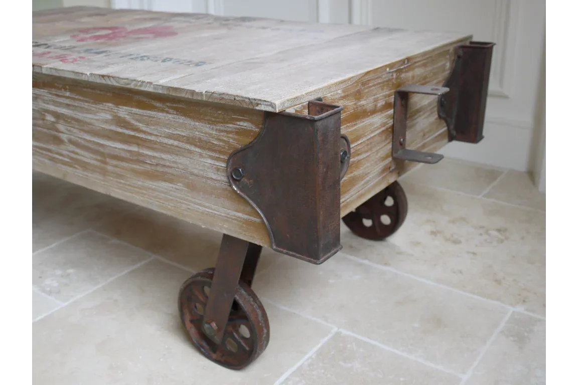 Industrial coffee table with rustic wood top and metal wheels on tiled floor