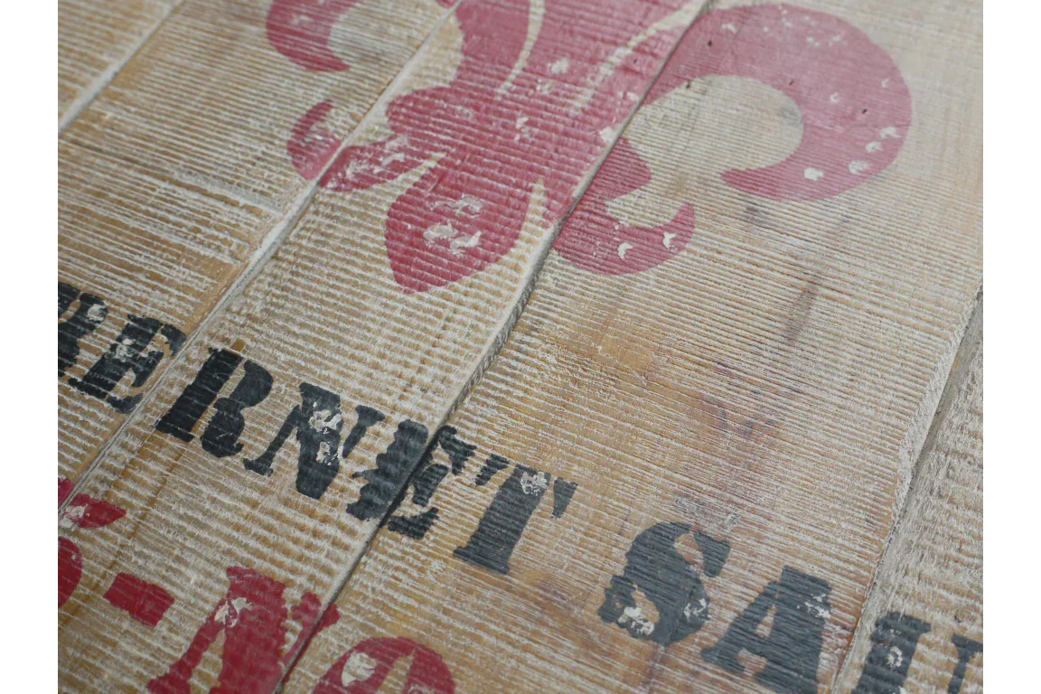distressed wood furniture surface with red fleur-de-lis and black stencilled lettering