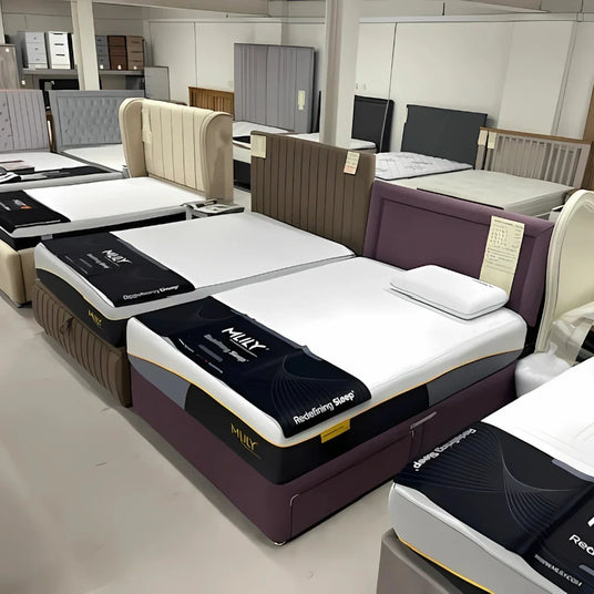 Display of upholstered beds and mattresses in furniture showroom