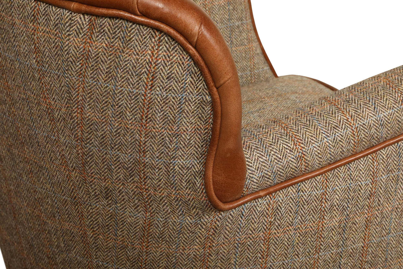Close-up of tweed armchair with brown leather piping and herringbone fabric pattern