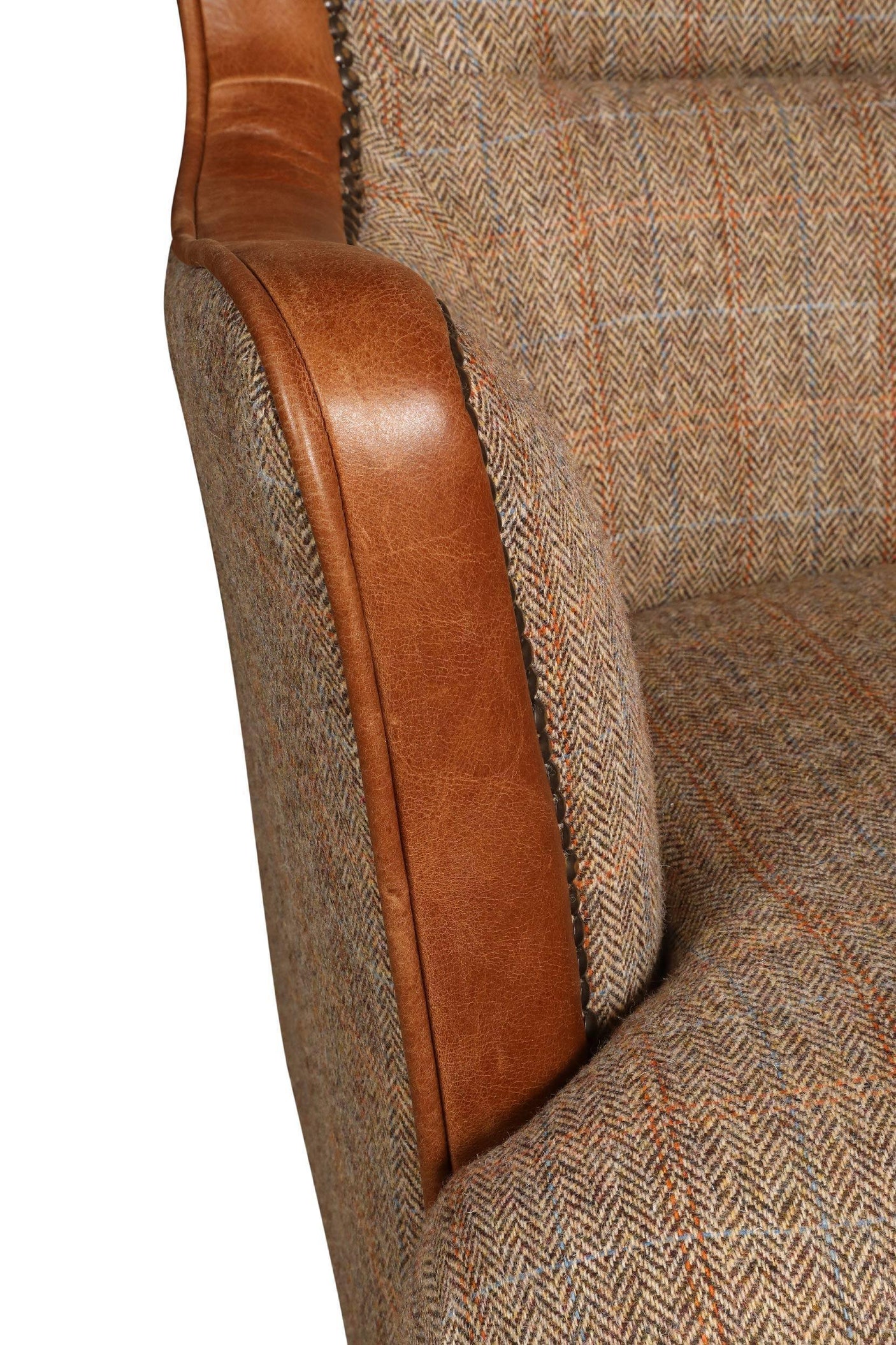 Close-up of armchair with brown leather armrest and patterned fabric upholstery