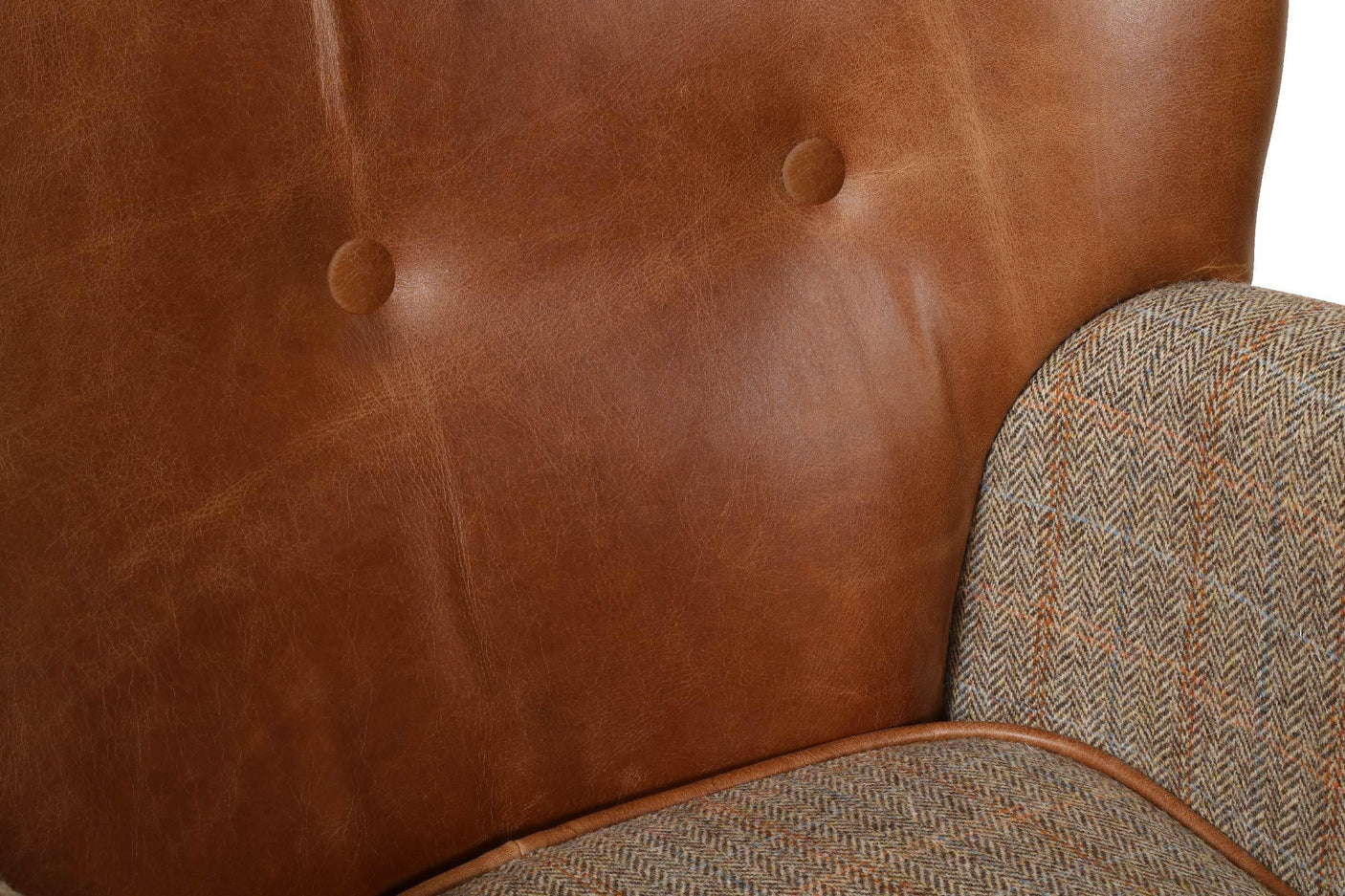 Close-up of brown leather armchair backrest with herringbone fabric arm detail