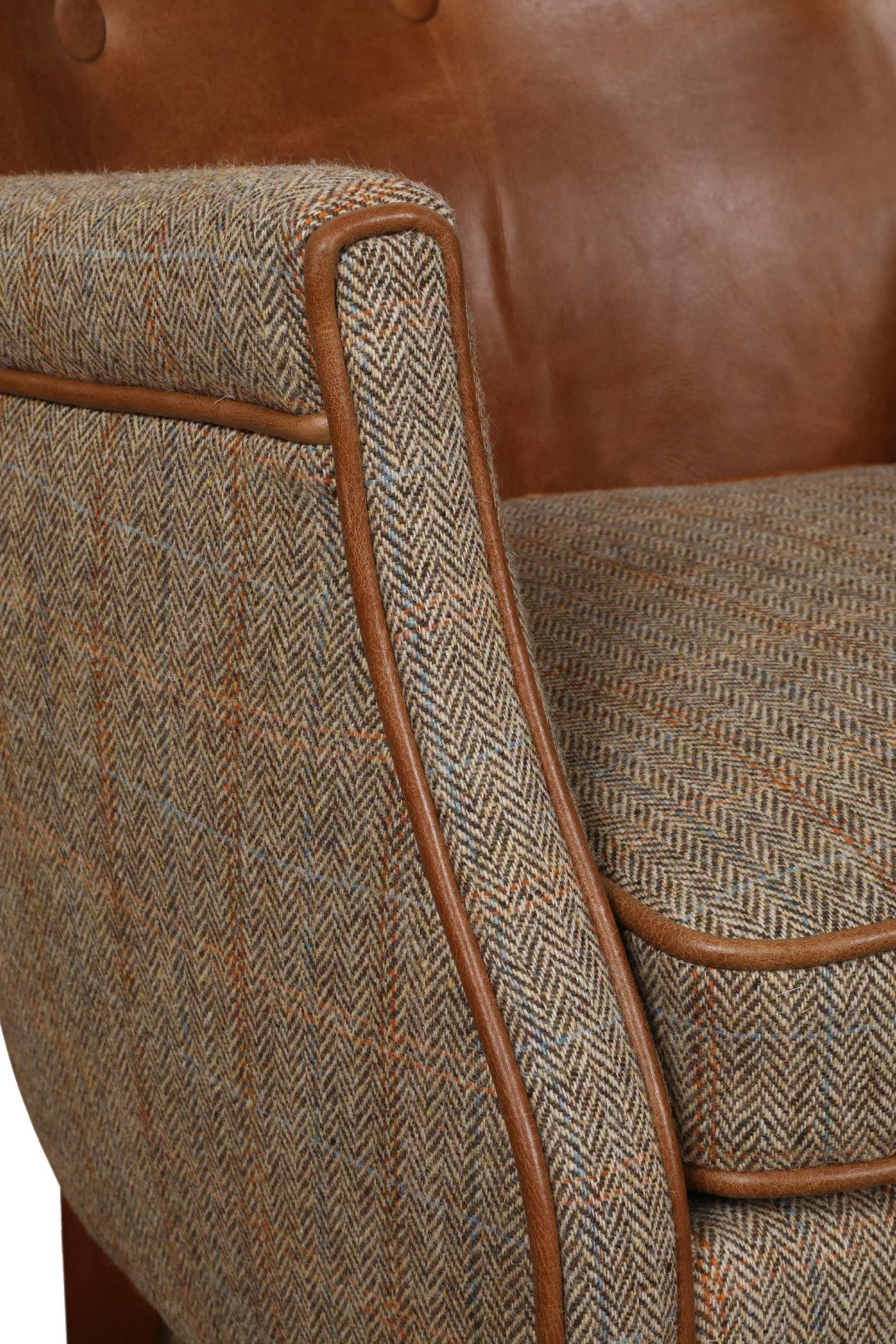 Closeup of tweed armchair with brown leather backrest and herringbone fabric upholstery