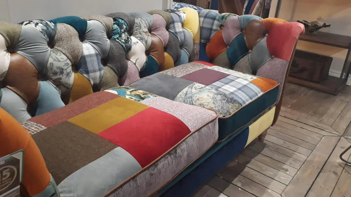 Patchwork fabric sofa with buttoned backrest and multicolored cushions on wooden floor