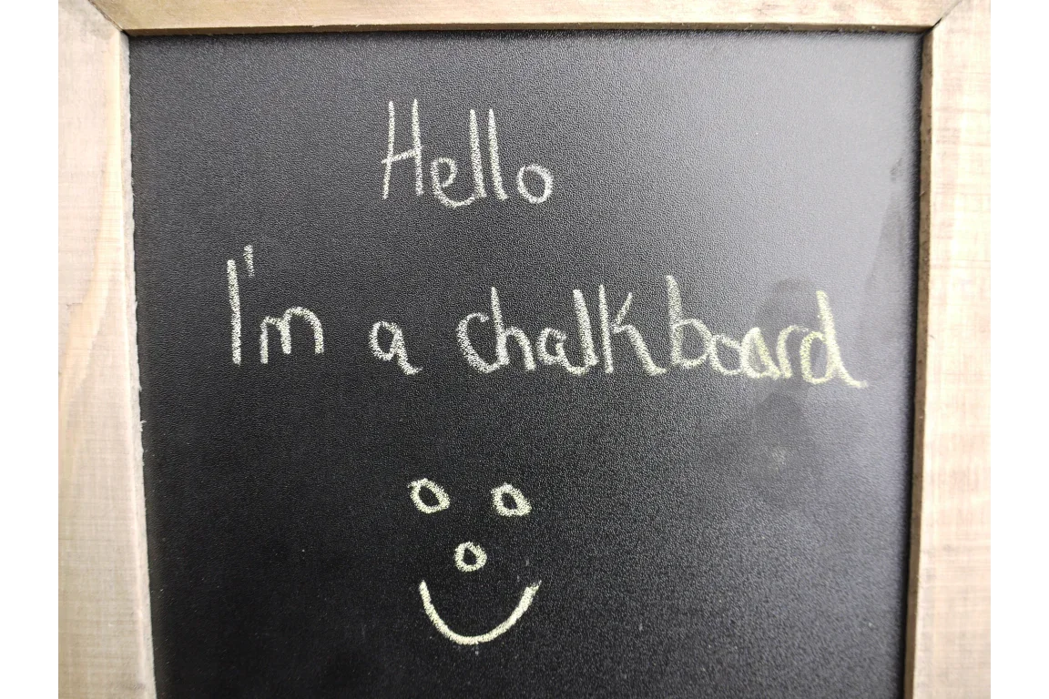 Rectangular framed chalkboard with handwritten chalk message and smiley face