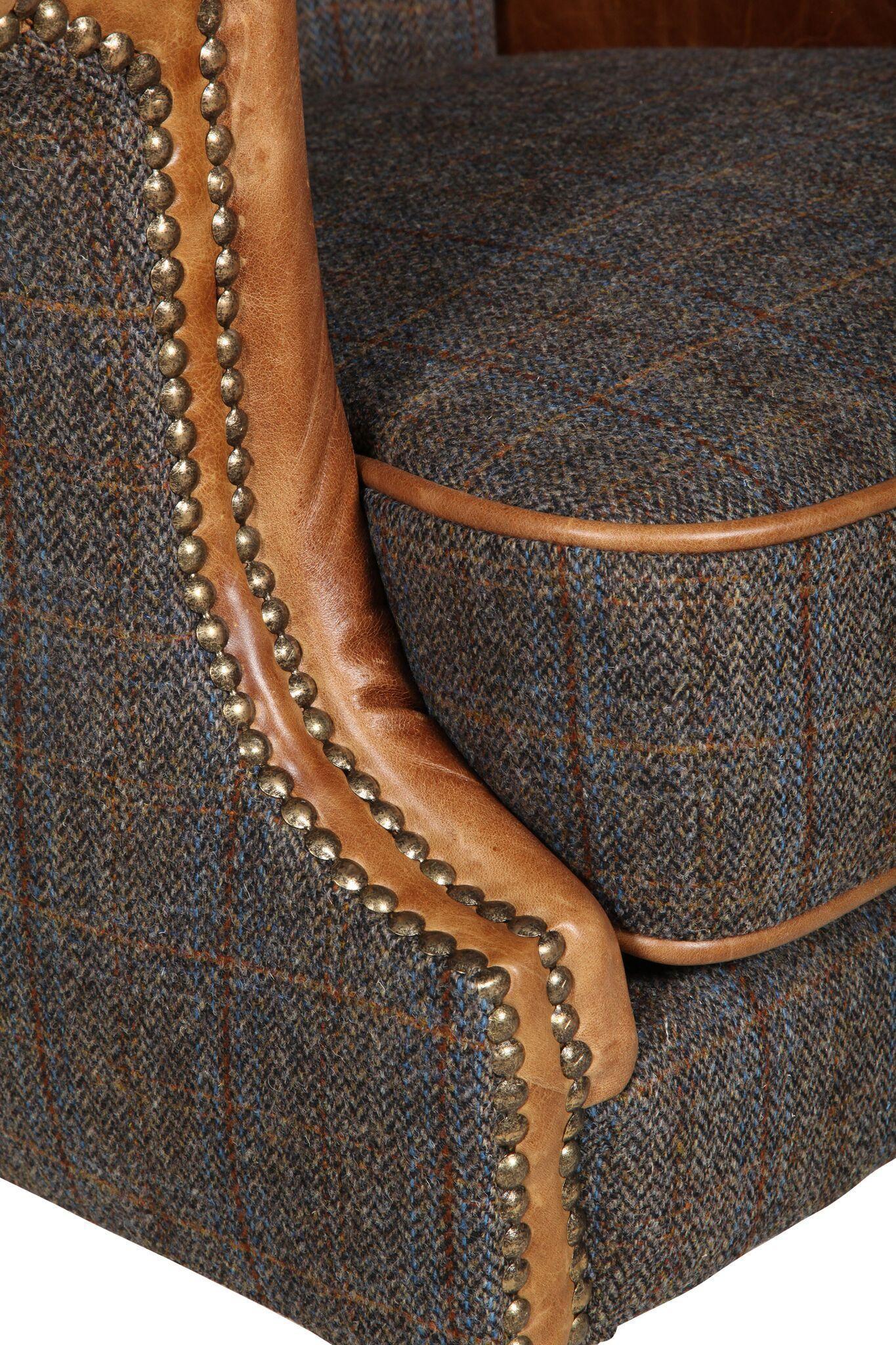 Close-up of tweed armchair with brown leather trim and brass stud detailing