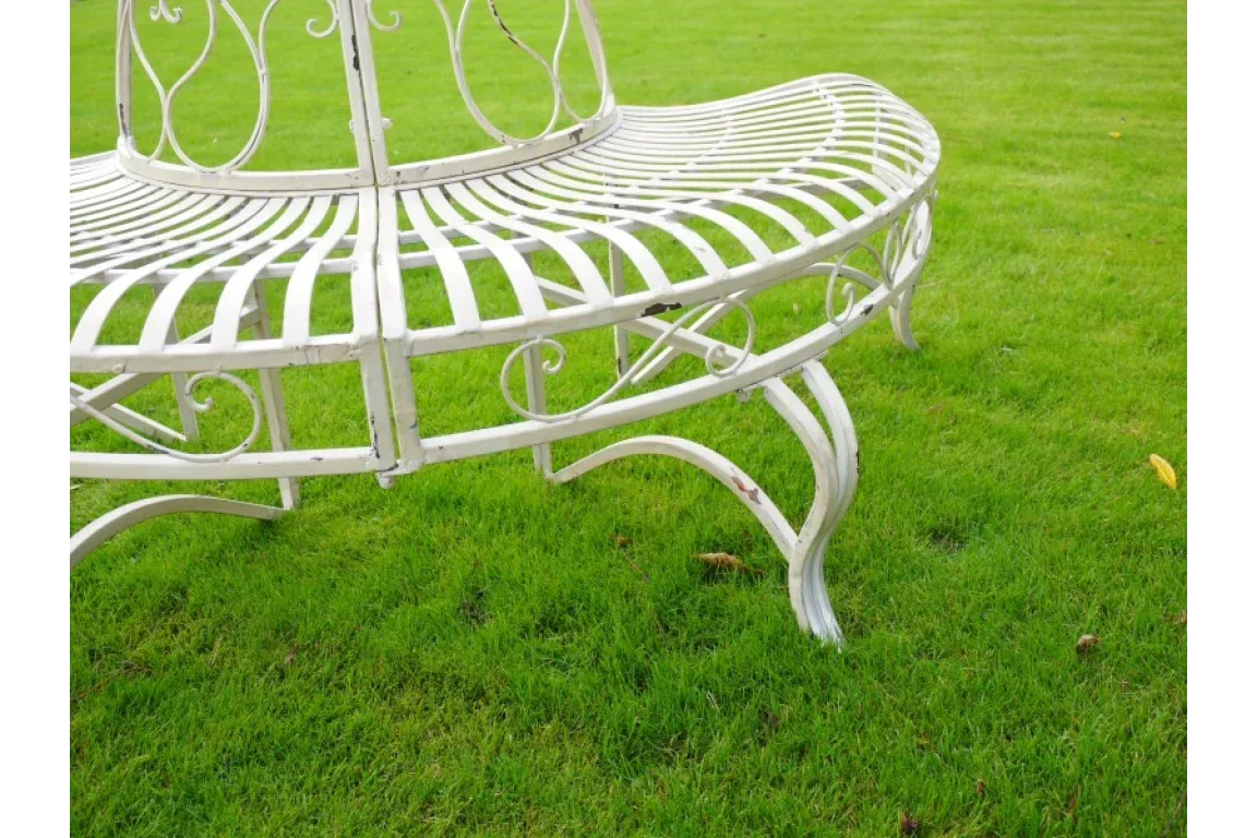 White metal garden bench with curved seat and decorative scrollwork on green lawn