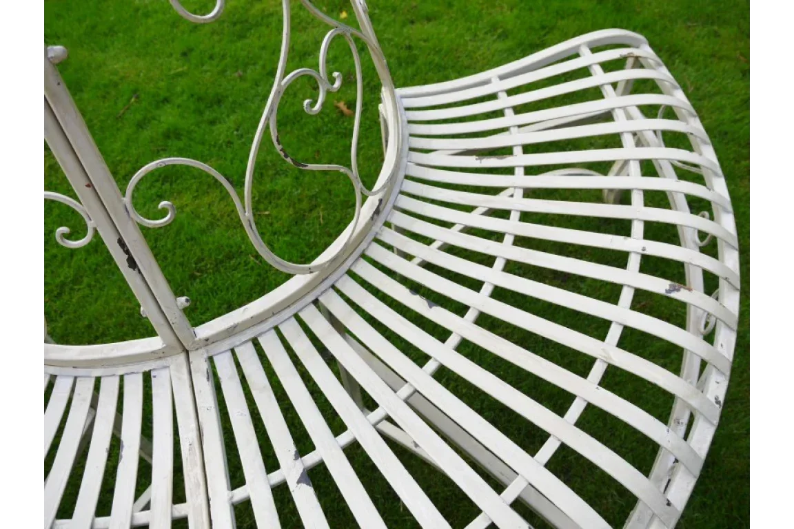White metal garden bench with curved slatted seat and decorative backrest on grass