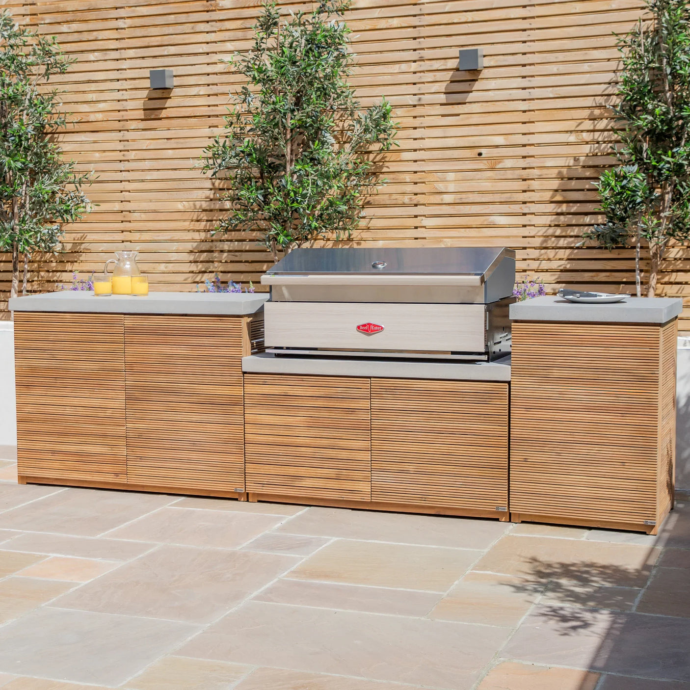 Outdoor kitchen unit with stainless steel barbecue and wood-effect cabinets on patio