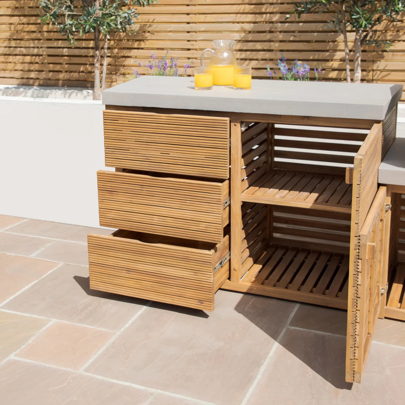 Outdoor wooden storage cabinet with slatted drawers and doors, grey stone top, patio setting