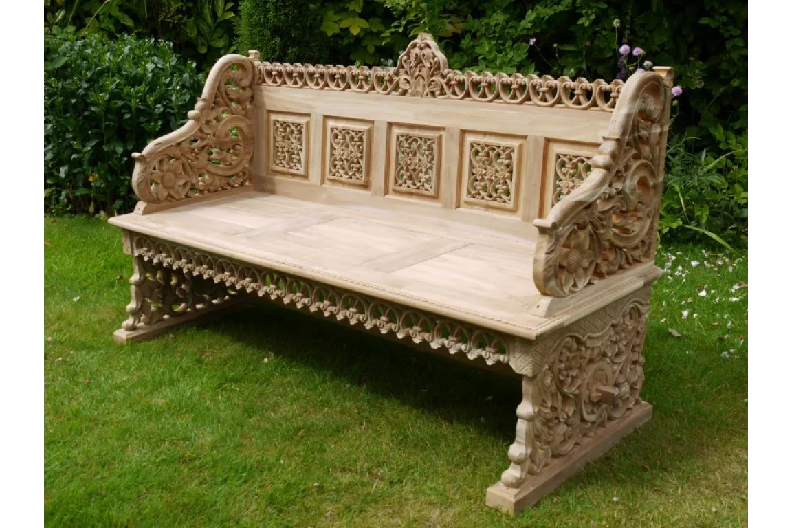 Hand carved wooden garden bench with intricate floral detail on grass