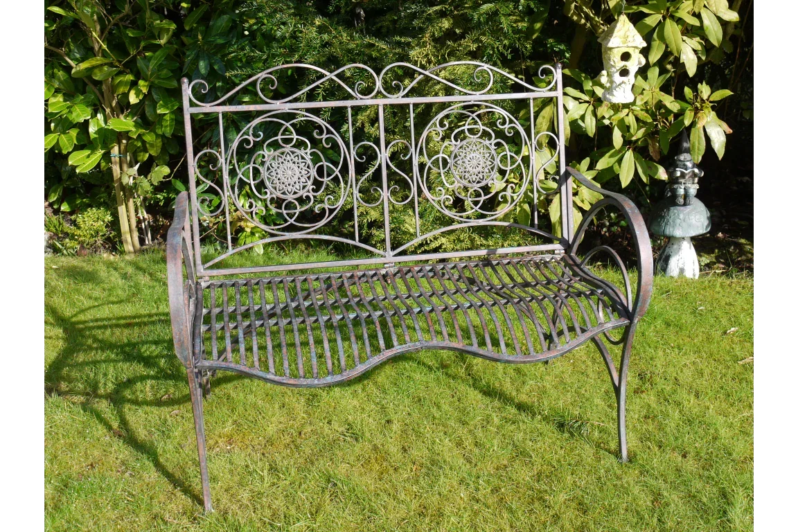Metal garden bench with ornate scrollwork backrest on lawn