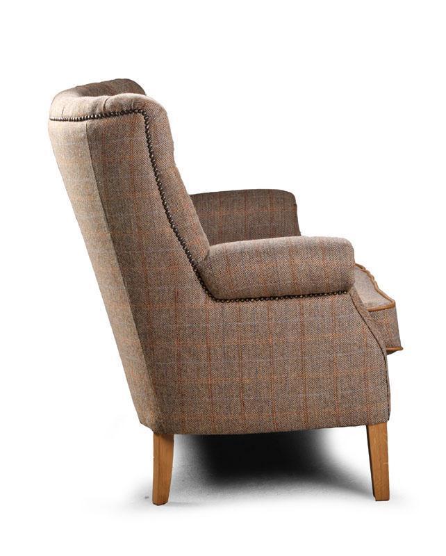 Side view of tweed armchair with wooden legs and nailhead trim