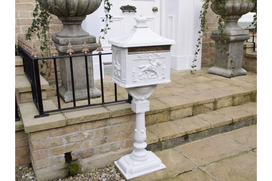 white cast iron post box with embossed lion design on pedestal by front steps