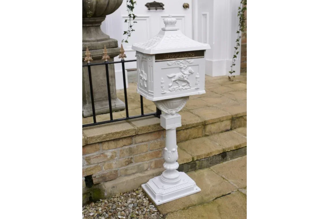 White cast iron post box with embossed detailing on patio near brick steps