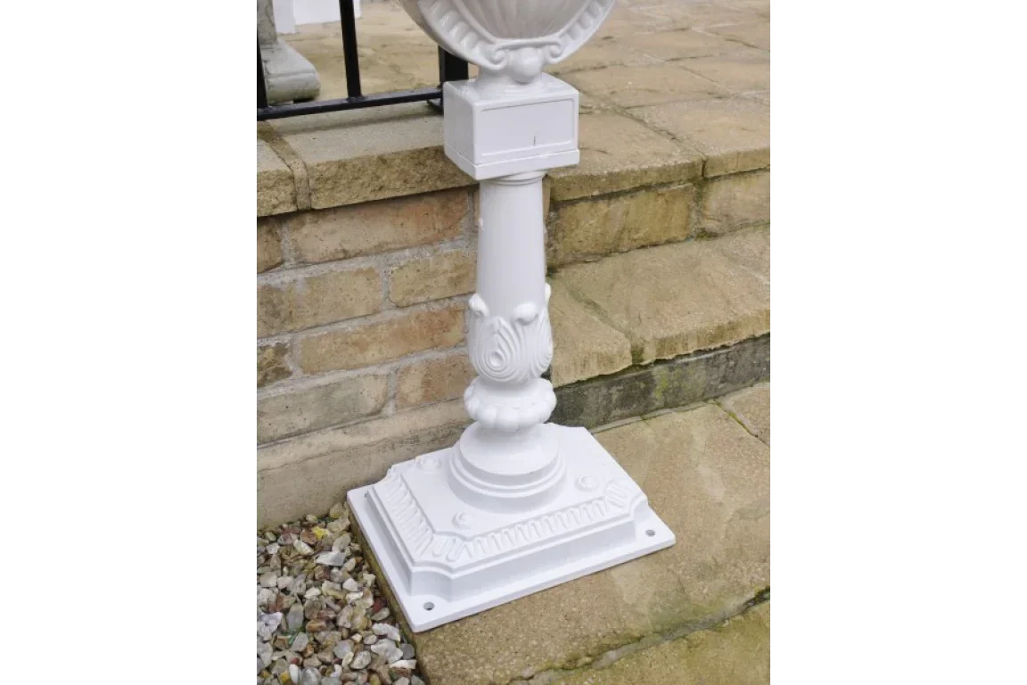 White decorative pedestal base for garden planter on stone steps