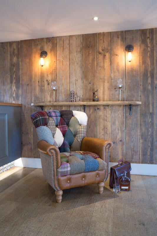 Patchwork armchair with leather arms in rustic living room, whisky decanter and glass nearby