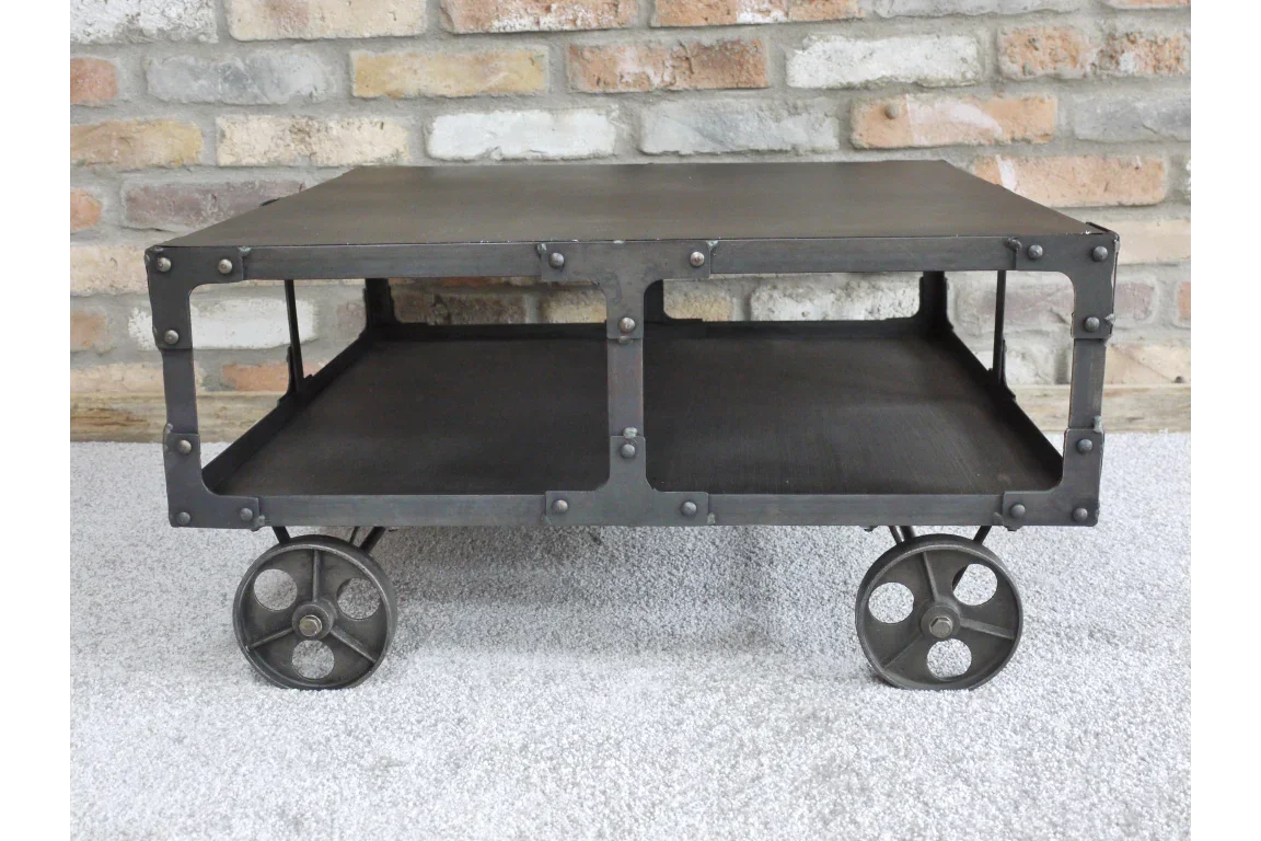 Industrial metal coffee table with open shelf and four wheel design against brick wall