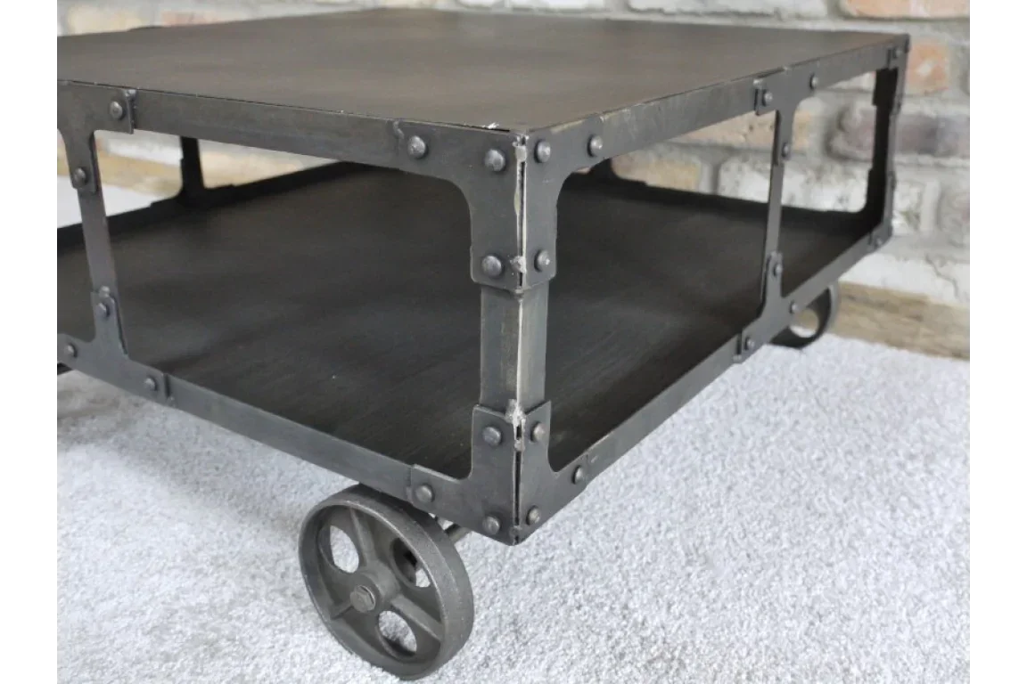 Industrial style coffee table with metal frame, rivet detail and large wheels on carpet