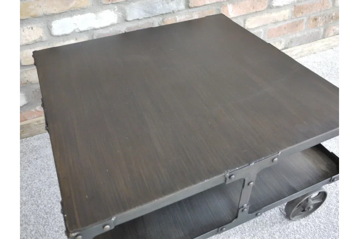 Industrial style black metal coffee table with shelf and castor wheels on carpet