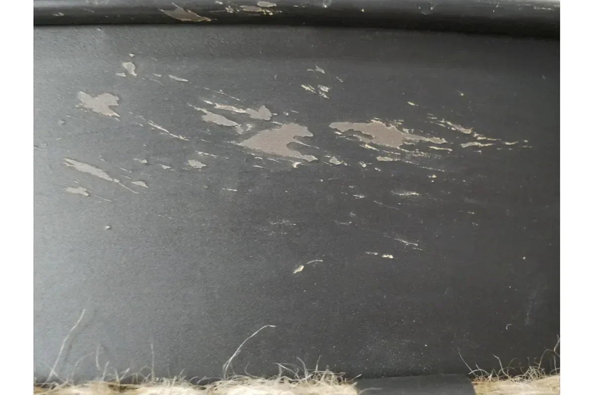 Close-up of black painted wood furniture surface with visible scuff marks and paint wear