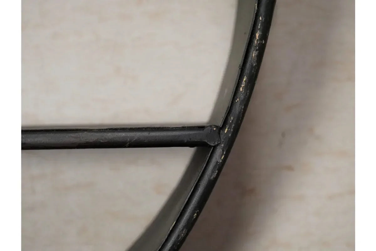Close-up of black metal furniture frame joint with worn finish against neutral background